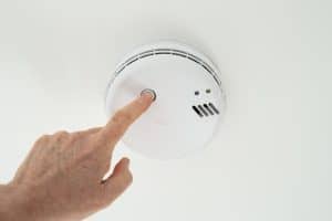 Homeowner checking smoke alarm batteries